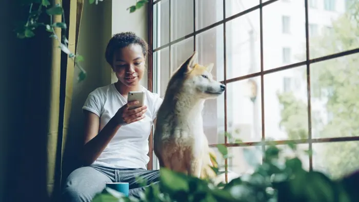 A woman relaxing by the window with her dog beside her